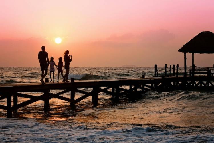 Family walking on pier at sunset